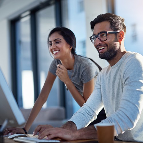 Two professionals collaborating at a computer in a modern office.
