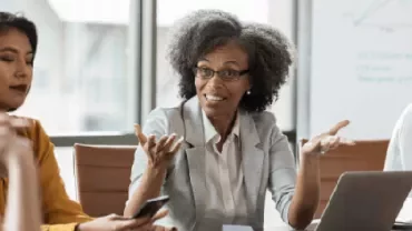 A woman explaining in the office and a group listening to her