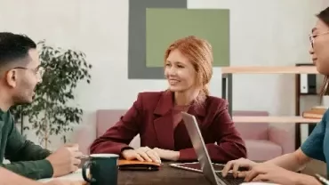 Professionals engaged in a collaborative discussion around a table in a modern office.