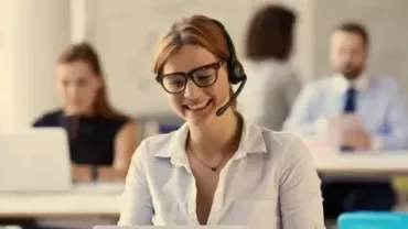 Professional using a headset while working at a desk in a modern office.