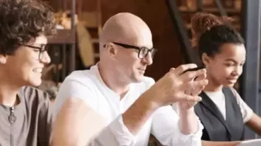 Professionals collaborating together around a table in a modern workplace setting.