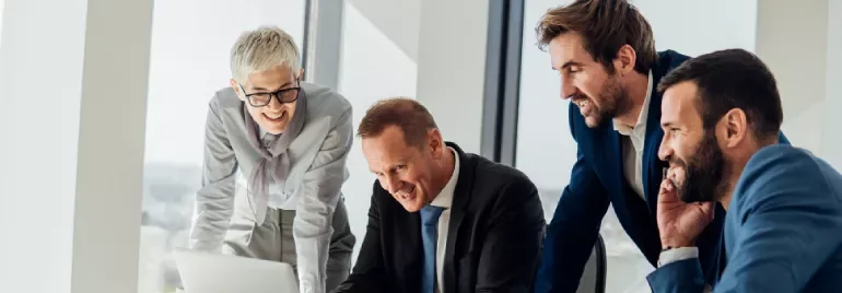 a group of people smiling looking to a computer in an office